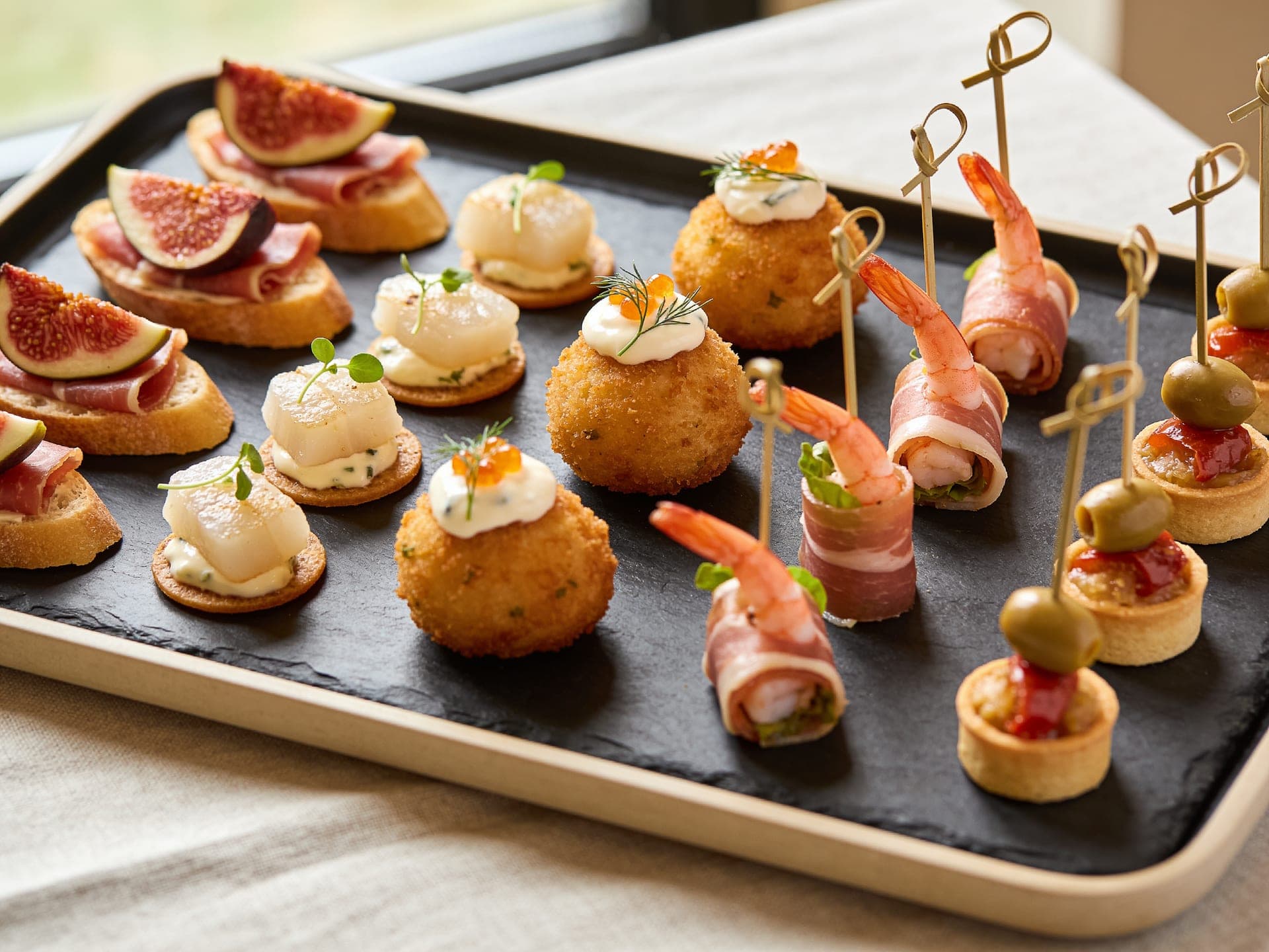 A tray of canapes: fig toasts, salt cod fritters and prawn rolls
